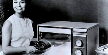 Imagen de una señora colocando un pollo en lo que probablemente sea el primer microondas inventado